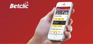 Aplicativo móvel da Betclic para apostas desportivas Mão segurando um smartphone com o aplicativo móvel da Betclic aberto, fundo vermelho com o logotipo da Betclic